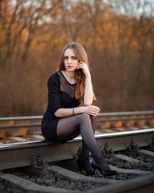 Ragazza al tramonto in natura in un vestito e scarpe nere