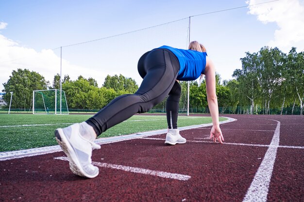 Ragazza all'inizio della pista da corsa. Correre sulla croce. Inizio sportivo. ragazza in posa sulla linea di partenza del tapis roulant. Stile di vita attivo. Concetto di andare avanti