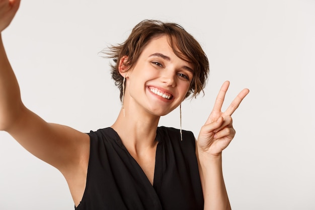 Ragazza alla moda allegra prendendo selfie sul cellulare