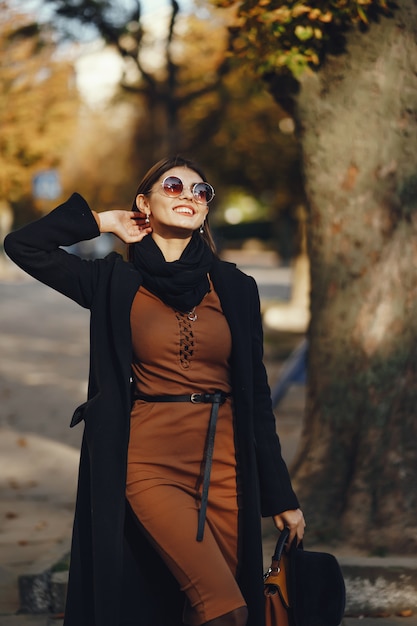 ragazza alla moda che cammina attraverso la città in una calda giornata di sole autunnale