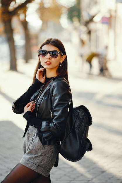 ragazza alla moda che cammina attraverso la città in una calda giornata di sole autunnale