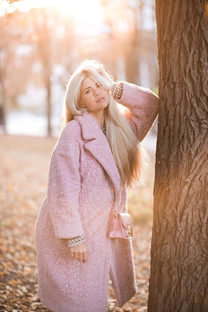 Ragazza alla moda che indossa soffice cappotto invernale in posa nel parco