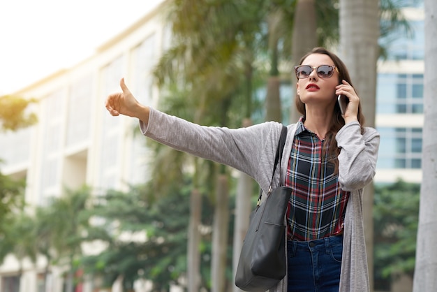 Ragazza alla moda che prende un taxi in città