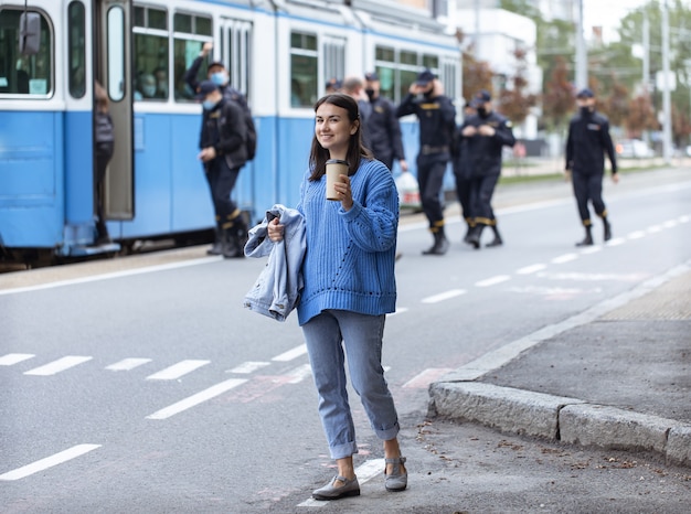 Ragazza alla moda con caffè per fare una passeggiata in città.