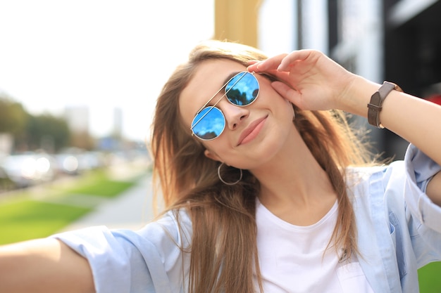 Ragazza alla moda hipster cool bere cocktail sullo sfondo della città urbana.