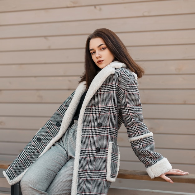 Ragazza alla moda in abiti di moda vicino a una parete in legno