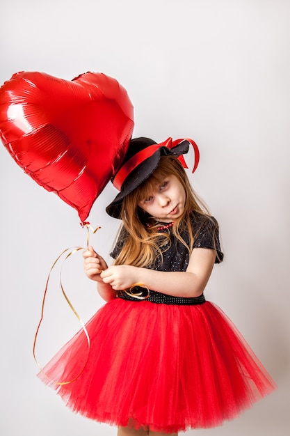 Ragazza alla moda in abito e cappello con palloncino a forma di cuore rosso