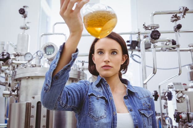 Ragazza alla moda in giacca di jeans tenendo becher di birra