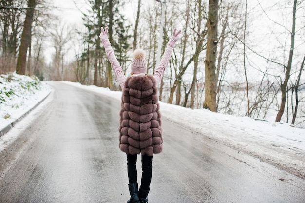 Ragazza alla moda in pelliccia e copricapo al giorno d'inverno sulla strada.