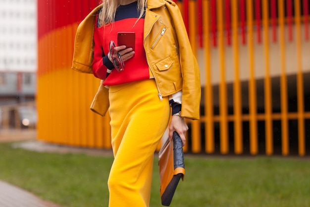 Ragazza alla moda in piedi sulla strada in vestiti di colore giallo brillante