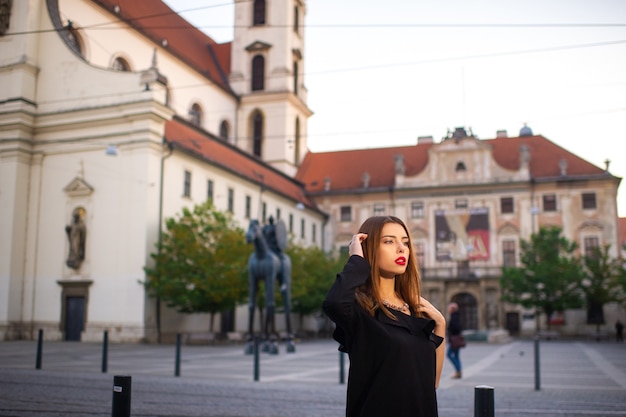 Ragazza alla moda in un abito nero sulla strada della città di Brno al mattino