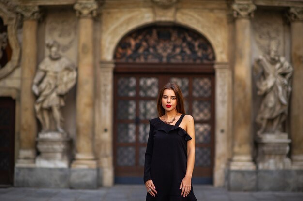 Ragazza alla moda in un abito nero sulla strada della città di Brno al mattino