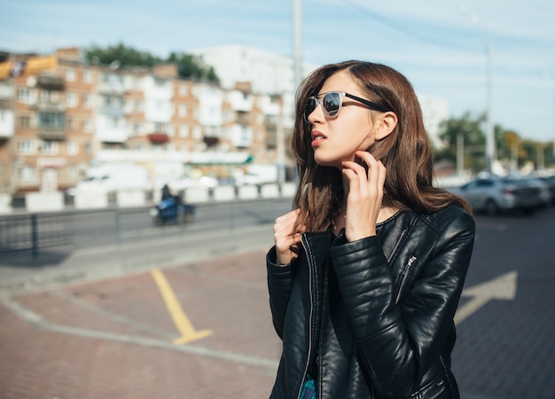 Ragazza alla moda urbana che posa in una giacca di pelle all'aperto in città