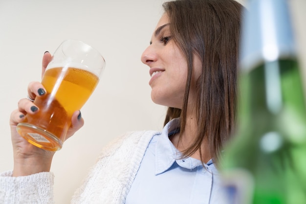 Ragazza allegra che beve birra dai bicchieri