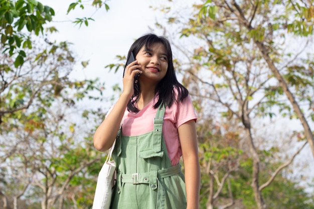 Ragazza allegra che utilizza un telefono cellulare e che tiene un concetto di stile di vita del libro