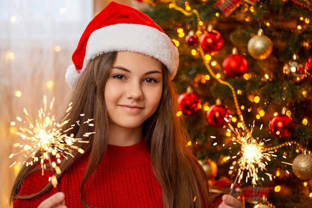 Ragazza allegra con fuochi del Bengala vicino all'albero di Natale Celebrando il concetto di Natale