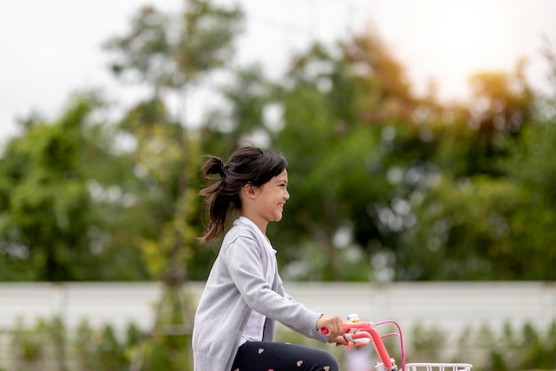 Ragazza allegra felice del bambino che guida una bici nel parco nella natura