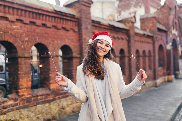 Ragazza allegra in un cappello di Natale che sorride alla macchina fotografica