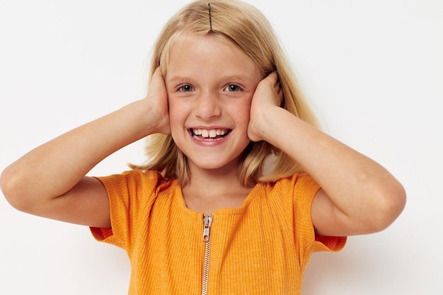 Ragazza allegra in una maglietta gialla che posa le emozioni sullo sfondo chiaro