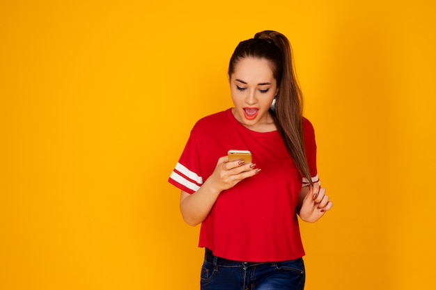 Ragazza allegra positiva che indossa una maglietta rossa su fondo giallo