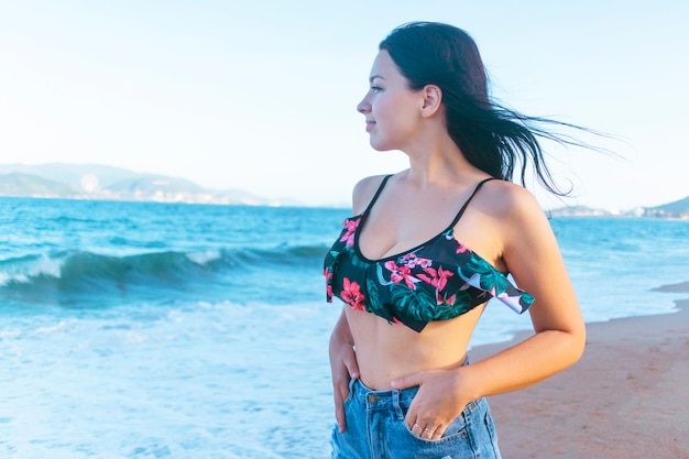 Ragazza allegra rilassata felice che gode del bel tempo su una spiaggia al tramonto