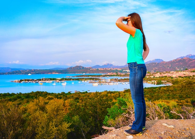 Ragazza allo scenario del Golfo Aranci in Costa Smeralda, Sardegna in Italia in estate. Donna al Paesaggio della provincia di Sassari vicino a Olbia e Cagliari. Nel Mar Mediterraneo. Yacht, barche. Tecnica mista.