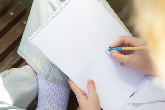 Ragazza anonima che prende appunti o disegna nella panoramica del libro di carta bianca