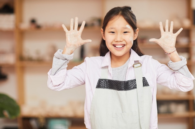 Ragazza asiatica allegra in classe di ceramica