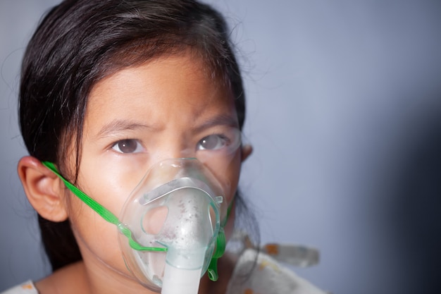 Ragazza asiatica bambino bisogno di nebulizzazione da ottenere maschera inalatore sul viso