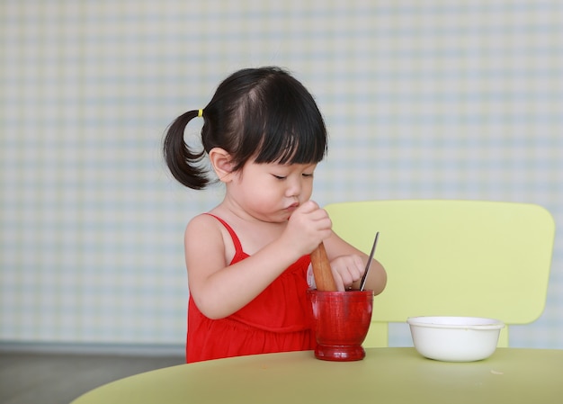 Ragazza asiatica bambino gioca per rendere l&#39;insalata di papaya verde o