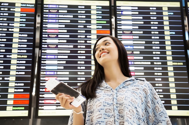 ragazza asiatica che controlla il volo all&#39;aeroporto