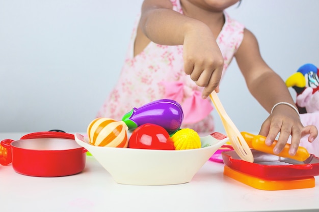 Ragazza asiatica che gioca cucina del giocattolo