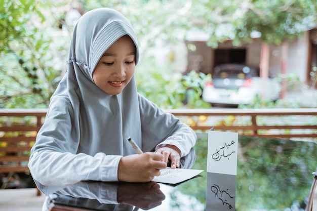 Ragazza asiatica che indossa un velo che fa la cartolina d'auguri di eid mubarak