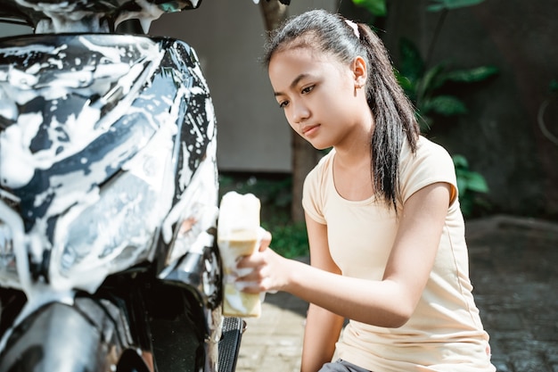 Ragazza asiatica che lava una motocicletta