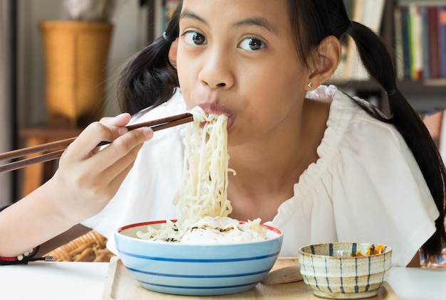 Ragazza asiatica che mangia le tagliatelle istantanee della Corea