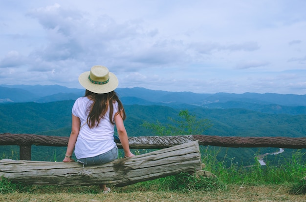 Ragazza asiatica che si siede sul legno e guardando la vista