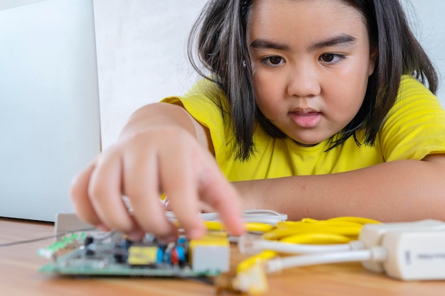 Ragazza asiatica che usa un laptop mentre assembla un robot da mattoni di plastica STEM Education for kids