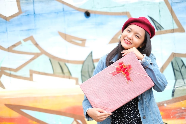 Ragazza asiatica con confezione regalo su sfondo colorato