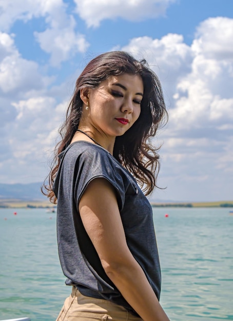 Ragazza asiatica con i capelli lunghi che posa contro il cielo