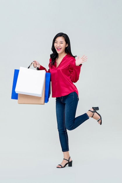 Ragazza asiatica con i sacchetti della spesa che si sente emozionata per la promozione di vendita