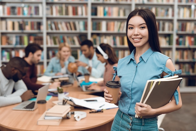 Ragazza asiatica con note e caffè in libreria.