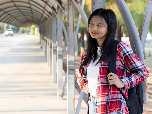 Ragazza asiatica con un libro e uno zaino a scuola