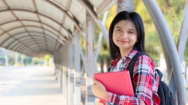 Ragazza asiatica con un libro e uno zaino a scuola