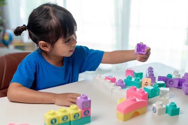 Ragazza asiatica del bambino che gioca i blocchi creativi del giocattolo per homeschooling