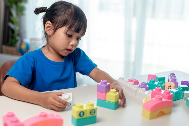 Ragazza asiatica del bambino che gioca i blocchi creativi del giocattolo per homeschooling