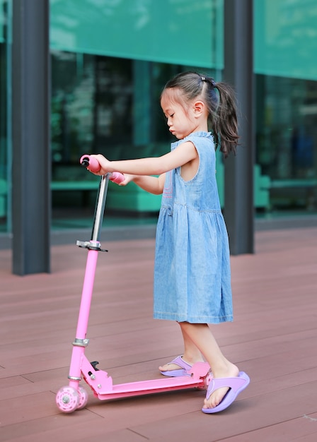 Ragazza asiatica del bambino che gioca motorino