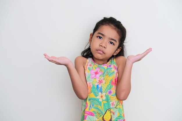 Ragazza asiatica del bambino che guarda la macchina fotografica e mostra un gesto confuso