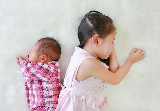 Ragazza asiatica del bambino e neonato infantile che dorme sul fondo bianco della pelliccia.