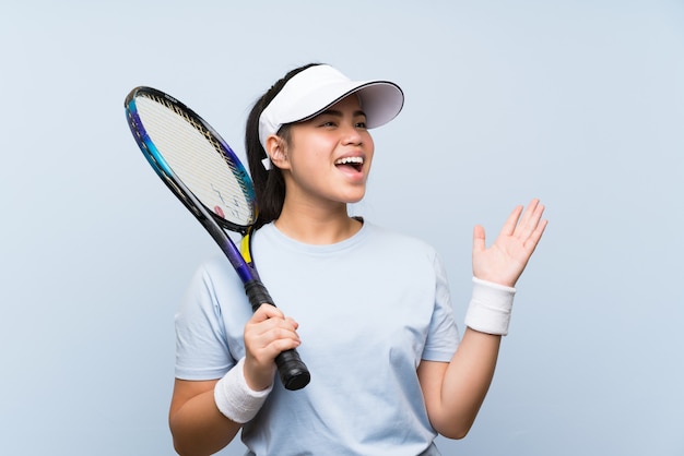 Ragazza asiatica del giovane adolescente che gioca a tennis con l'espressione facciale di sorpresa