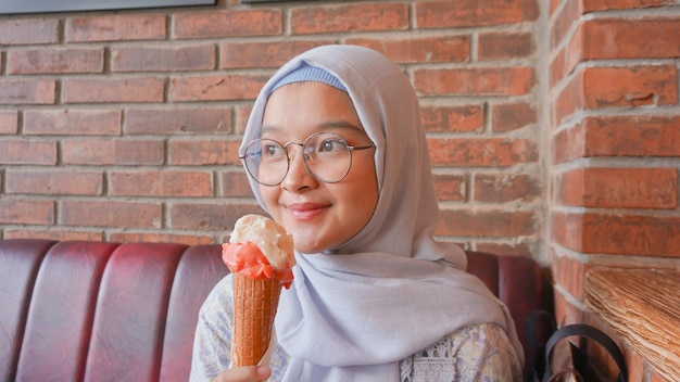 Ragazza asiatica dell'hijab mentre si gusta il gelato al gelato